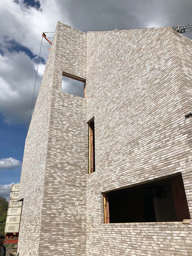 Tall slender porcelain bottle with natural clay textured body and cork stopper.